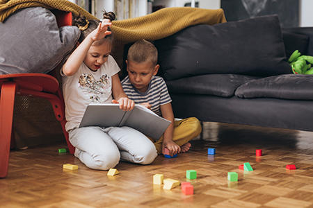 Children reading together in a cozy home environment supporting early reading daycare Kyle