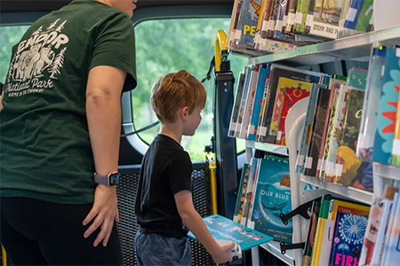 Child selecting books from mobile library supporting early reading daycare Kyle